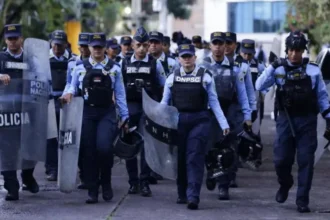 A group of uniformed police officers with shields and protective gear walking together during heightened election security.